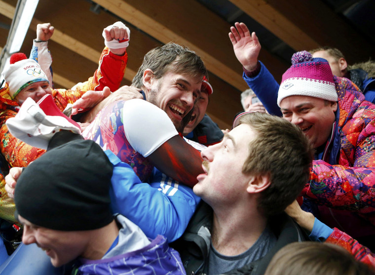 Image: Russia's Alexander Tretiakov (C) celebrates with friends and family after winning the men's skeleton event at the 2014 Sochi Winter Olympics